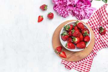 Delicious fresh red strawberries with Pink peony flowers. on a white kitchen table, place for text, top view