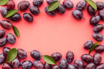 Purple plums with leaves top view. Food fruits background