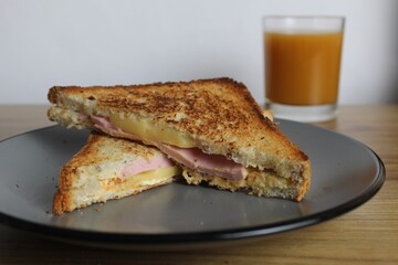 Food, avtrak. Sandwiches with ham cheese and vegetable elenium lie on a gray plate next to the juice of orange apricot on the table. Cooking breakfast
