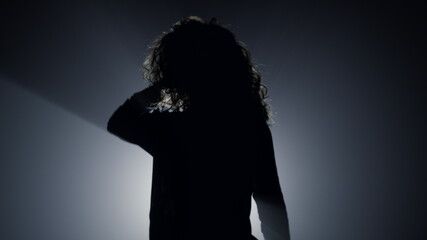 Silhouette sexy girl dancing in darkness. Beautiful woman touching hair.