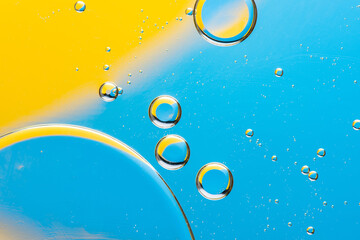 Beautiful macro photo of water droplets in oil with a yellow and blue background. Abstract art