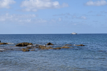 Rocky Shore with Blue Sky Horizon Sea & Distant Pleasure Boat