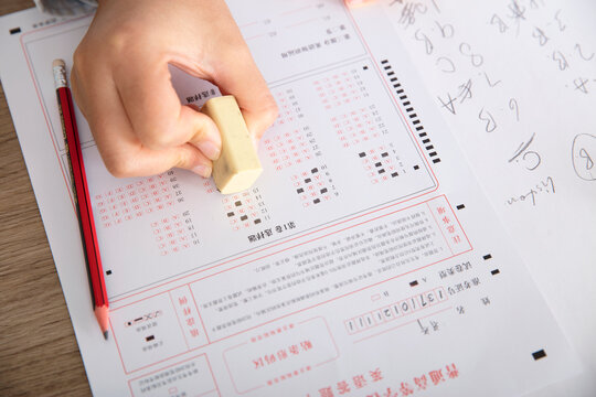 Close-up shot of examinee holding rubber to modify answer sheet