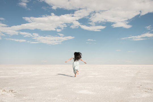 child running in blue dress on white salt flat in Bonneville Utah