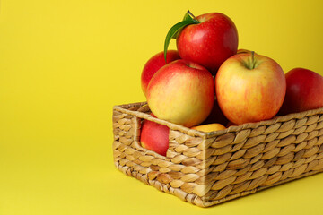 Basket with red apples on yellow background