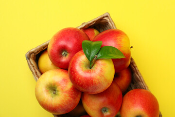 Basket with red apples on yellow background