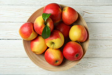 Bowl with red apples on white wooden table