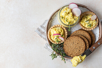 Plate with tartlets, multigrain crackers with egg pate or salad served with radish and thyme. Top view.