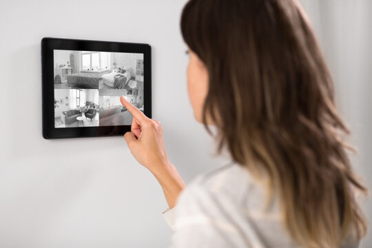 automation, security and technology concept - woman having video surveillance on tablet pc computer at smart home