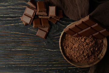 Tasty chocolate bars and powder on wooden table
