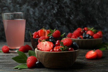 Bowls with berry mix and juice on wooden table
