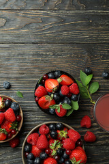 Naklejka na ściany i meble Bowls with berry mix and juice on wooden background
