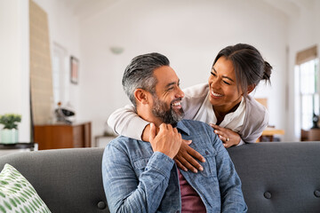 Mature multiethnic couple laughing and embracing at home - Powered by Adobe