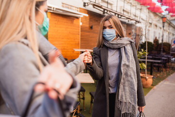 A beautiful young caucasian blonde woman greets a friend she met in town. Shopping during the COVID-19 coronavirus pandemic