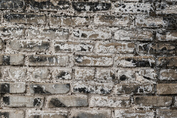Old brick wall from gray bricks. White salt patterns, black spots, cracks. Concept of an ancient structure.
