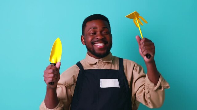 Brazilian Gardener Man Holding Garden Yellow Items In Studio Blue Background