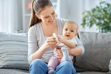 family, motherhood and people concept - happy smiling mother and little baby playing with rattle at home