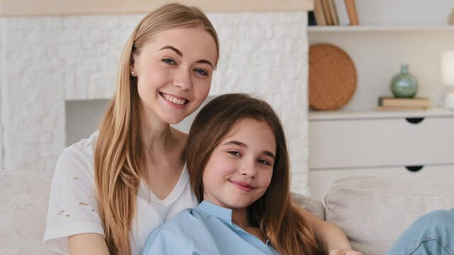 Close up view happy two generation women family young lovely mom and little adorable 10s daughter cuddling seated on couch at home enjoying sweet tender moment together at home, relations concept