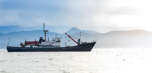 large fishing vessel on the background of hills and volcanoes