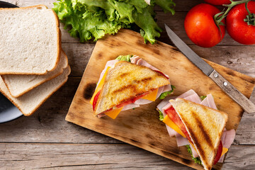 Sandwich with tomato,lettuce,ham and cheese on wooden table. Top view