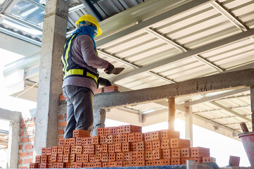 masonry worker make concrete wall by cement block and plaster at construction site