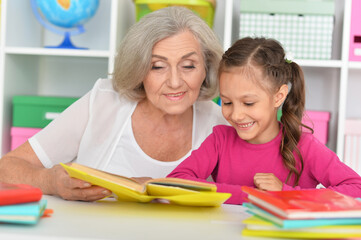 Little girl doing homework with her grandmother at home