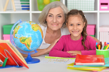 Little girl doing homework with her grandmother at home