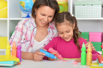 Porait of little cute girl with mother drawing at home