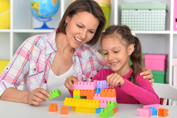 Cute little girl playing with colorful clay blocks at home