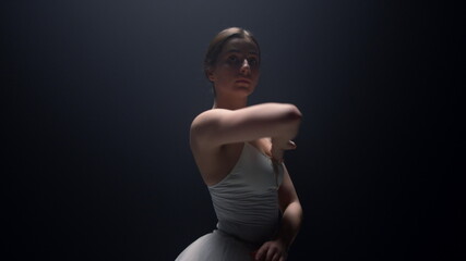 Tender ballerina looking camera in dark background. Ballet dancer dancing class