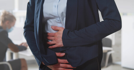 Cropped shot of businesswoman suffering with stomach ache in office