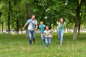 Fototapeta premium Portrait of happy young family running in summer park