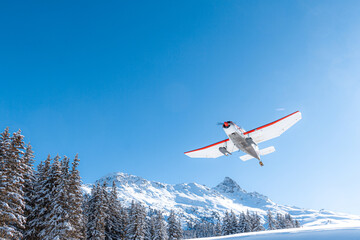 Propeller airplane taking off in mountain winter landscape 