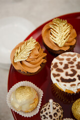 Festive table with sweet treats in the form of cakes and eclairs with custard and chocolate cream. Birthday gilded cupcakes
