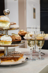 Festive table with sweet treats in the form of cakes and eclairs with custard and chocolate cream. Birthday gilded cupcakes