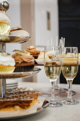 Festive table with sweet treats in the form of cakes and eclairs with custard and chocolate cream. Birthday gilded cupcakes