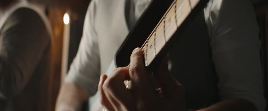 CU Caucasian male playing guitar during jazz band rehearsal in a recording studio. Shot with 2x anamorphic lens