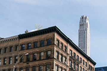 Obraz premium Cityscape of the neighborhood of Tribeca in Manhattan. Old commercial building against skyscraper on blue sky