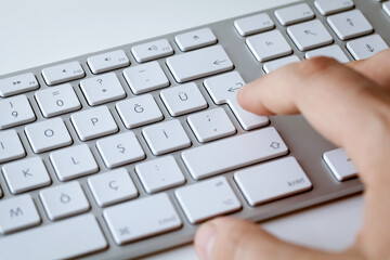 Modern computer keyboard white.Male hand touching the keyboard.White background isolated.