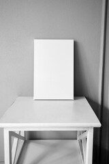 White canvas mockup, blank picture on wooden table in interior with grey wall