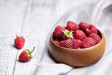 Fresh raspberries in wooden bowl on gray table. Red ripe raspberries, sweet berries