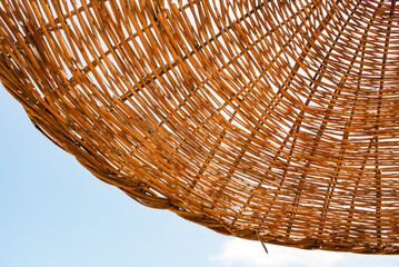 Wicker beach umbrella against the sky