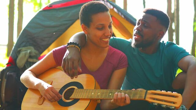 african people on camping trip welcoming a new day in summer park sing and play on guitar