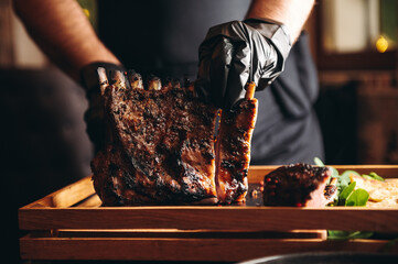 Chef cutting grilled roasted rack of lamb on wooden board