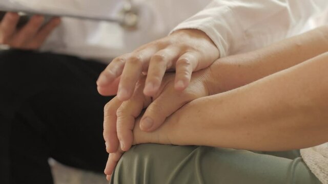 Male doctor nurse wearing white uniform shakes hands of senior grandmother patient