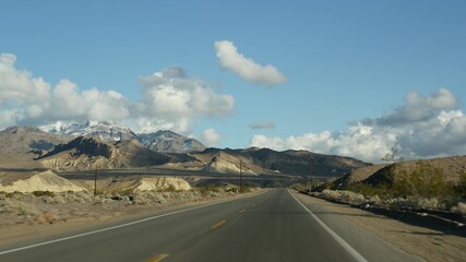 Road trip, driving auto from Death Valley to Las Vegas, Nevada USA. Hitchhiking traveling in America. Highway journey, dramatic atmosphere, clouds, mountain and Mojave desert wilderness. View from car