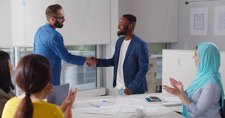 Young modern men in smart casual wear shaking hands while working in the creative office