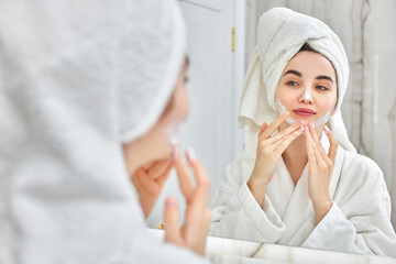 Obraz na płótnie Canvas woman in white bathrobes applying apply facial cream