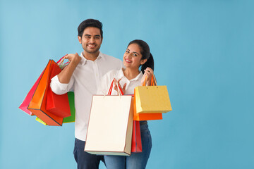 A YOUNG COUPLE PLAYFULLY POSING WITH SHOPPING BAGS IN HAND	