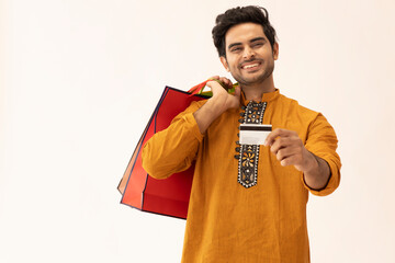A HAPPY YOUNG MAN POSING IN FRONT OF CAMERA HOLDING DEBIT CARD	
